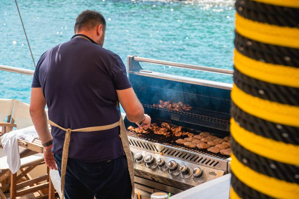 Chef grilling meat on deck during corporate boat events athens